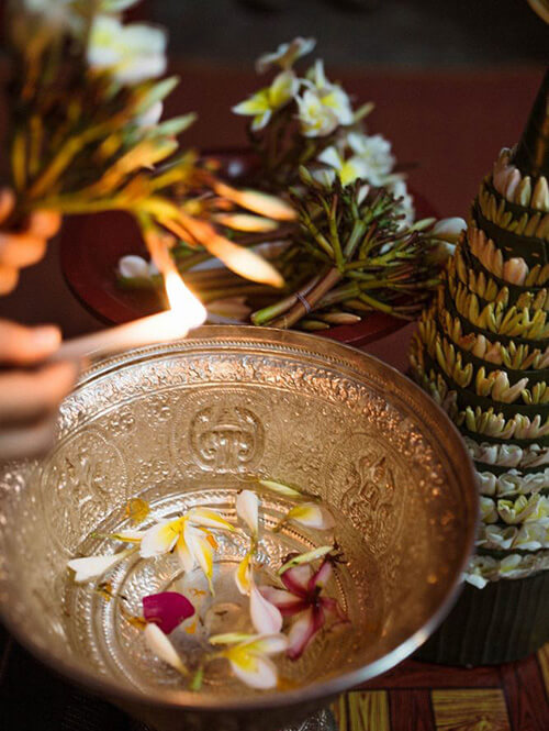 L’eau parfumée mélangée avec des fleurs pour arroser les effigies de Bouddha
